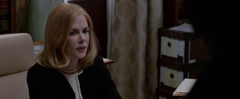 Movie still from “Secret in Their Eyes” (2015), directed by Billy Ray – A woman sitting at a table in front of a curtain; Close Up shot, Over the shoulder angle