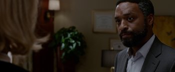 Movie still from “Secret in Their Eyes” (2015), directed by Billy Ray – A person in a room near a plant; Close Up shot, Over the shoulder angle