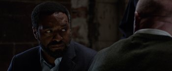 Movie still from “Secret in Their Eyes” (2015), directed by Billy Ray – A man in a suit looking at the camera; Close Up shot, Over the shoulder angle