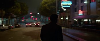Movie still from “Secret in Their Eyes” (2015), directed by Billy Ray – A man standing on a sidewalk at night; Wide shot, Over the shoulder angle