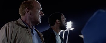Movie still from “Secret in Their Eyes” (2015), directed by Billy Ray – A couple of men standing next to each other in a stadium; Close Up shot, Low angle