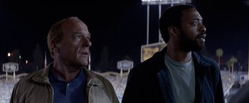 Movie still from “Secret in Their Eyes” (2015), directed by Billy Ray – Two men standing next to each other at a baseball game; Close Up shot, Low angle