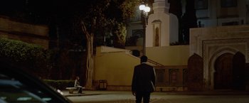 Movie still from “Secret in Their Eyes” (2015), directed by Billy Ray – A man standing on a sidewalk at night near a lamp post; Extreme Wide shot, Over the shoulder angle