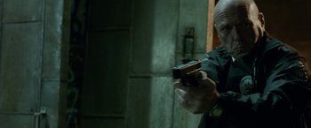 Movie still from “Secret in Their Eyes” (2015), directed by Billy Ray – A person holding a gun in a room; Close Up shot, Over the shoulder angle
