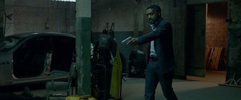 Movie still from “Secret in Their Eyes” (2015), directed by Billy Ray – A man in a suit and tie holding a wii controller; Medium shot, Over the shoulder angle