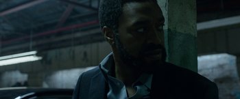 Movie still from “Secret in Their Eyes” (2015), directed by Billy Ray – A person wearing a suit and beard; Close Up shot, Over the shoulder angle