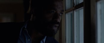 Movie still from “Secret in Their Eyes” (2015), directed by Billy Ray – A person with a beard looking out a window; Close Up shot, Over the shoulder angle
