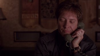 Movie still from “Secretary” (2002), directed by Steven Shainberg – A man talking on a phone while sitting in a room; Close Up shot, Low angle
