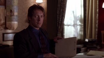 Movie still from “Secretary” (2002), directed by Steven Shainberg – A man in a suit and tie holding an open laptop computer; Close Up shot, Low angle