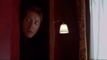 Movie still from “Secretary” (2002), directed by Steven Shainberg – A man looking out a window at a light; Close Up shot, Low angle