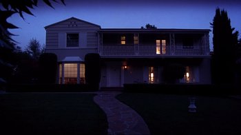 Movie still from “Secretary” (2002), directed by Steven Shainberg – A house that is lit up at night time; Extreme Wide shot, Low angle