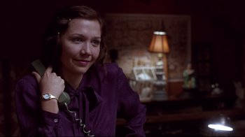 Movie still from “Secretary” (2002), directed by Steven Shainberg – A woman in a purple shirt is holding a phone to her ear; Close Up shot, Over the shoulder angle