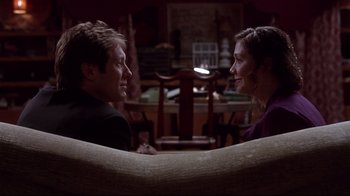 Movie still from “Secretary” (2002), directed by Steven Shainberg – A man and a woman sitting on a couch looking at one another; Medium shot, Over the shoulder angle