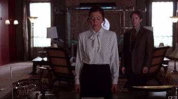 Movie still from “Secretary” (2002), directed by Steven Shainberg – A woman standing in front of a man in front of a table; Medium shot, Over the shoulder angle