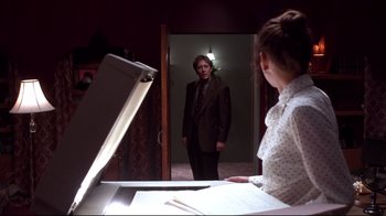 Movie still from “Secretary” (2002), directed by Steven Shainberg – A man standing in front of a woman in front of an open door; Medium shot, Over the shoulder angle