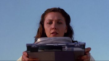 Movie still from “Secretary” (2002), directed by Steven Shainberg – A woman is holding an electronic device up to her face; Close Up shot, Low angle