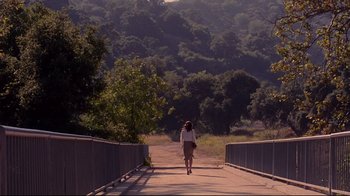 Movie still from “Secretary” (2002), directed by Steven Shainberg – A woman walking across a bridge over a river; Extreme Wide shot, High angle