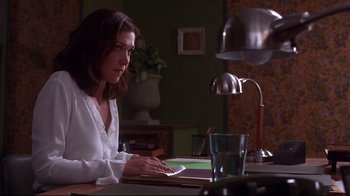 Movie still from “Secretary” (2002), directed by Steven Shainberg – A woman sitting at a table writing on a piece of paper; Medium shot, Low angle