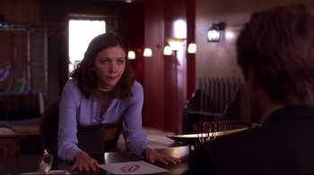 Movie still from “Secretary” (2002), directed by Steven Shainberg – A woman sitting at a table in front of a man; Medium shot, Over the shoulder angle