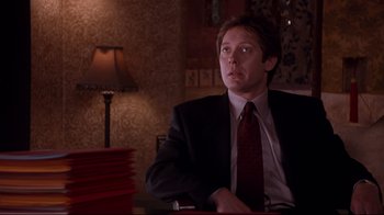 Movie still from “Secretary” (2002), directed by Steven Shainberg – A man in a suit sitting in front of a lamp; Medium shot, Low angle