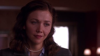 Movie still from “Secretary” (2002), directed by Steven Shainberg – A person wearing a suit and pearl necklace; Close Up shot, Over the shoulder angle