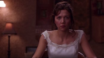 Movie still from “Secretary” (2002), directed by Steven Shainberg – A woman in a white dress sitting in front of a window; Close Up shot, Over the shoulder angle