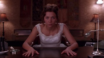 Movie still from “Secretary” (2002), directed by Steven Shainberg – A woman sitting at a table in a white dress; Medium shot, High angle