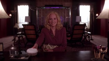 Movie still from “Secretary” (2002), directed by Steven Shainberg – A woman sitting at a table in a room; Medium shot, Low angle