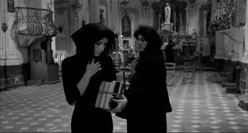 Movie still from “Seduced and Abandoned” (1964), directed by Pietro Germi – A couple of women standing next to each other in a room; Medium shot, High angle