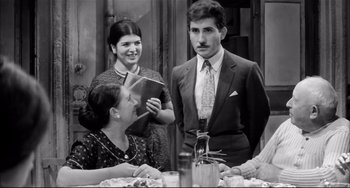 Movie still from “Seduced and Abandoned” (1964), directed by Pietro Germi – A group of people sitting around a table; Medium shot, Over the shoulder angle