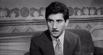 Movie still from “Seduced and Abandoned” (1964), directed by Pietro Germi – A man in a suit and tie with a fake mustache; Close Up shot, Low angle