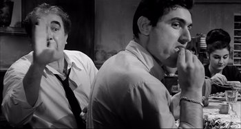 Movie still from “Seduced and Abandoned” (1964), directed by Pietro Germi – Two men are sitting in a room and one of them is smoking a cigarette; Close Up shot, Low angle