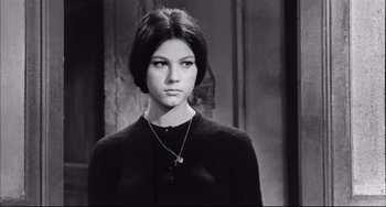 Movie still from “Seduced and Abandoned” (1964), directed by Pietro Germi – A young woman in a black sweater with a cross necklace; Close Up shot, Low angle