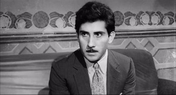 Movie still from “Seduced and Abandoned” (1964), directed by Pietro Germi – Black and white photograph of a man in a suit and tie; Close Up shot, Low angle