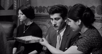 Movie still from “Seduced and Abandoned” (1964), directed by Pietro Germi – A black and white photo of a man holding a tray of food; Medium shot, High angle