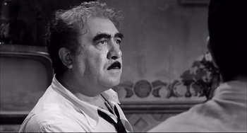 Movie still from “Seduced and Abandoned” (1964), directed by Pietro Germi – An older man wearing a neck tie looking up at the sky; Close Up shot, Low angle