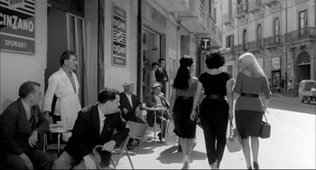 Movie still from “Seduced and Abandoned” (1964), directed by Pietro Germi – A black and white photo of people walking down a street; Wide shot, Low angle