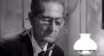 Movie still from “Seduced and Abandoned” (1964), directed by Pietro Germi – An old man with a stethoscope around his neck; Close Up shot, Low angle
