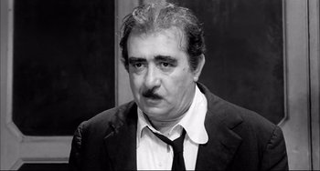 Movie still from “Seduced and Abandoned” (1964), directed by Pietro Germi – An older man wearing a suit and a tie; Close Up shot, High angle