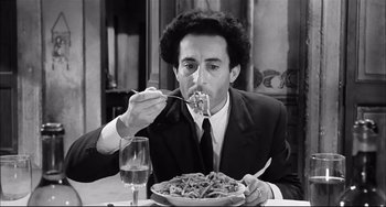 Movie still from “Seduced and Abandoned” (1964), directed by Pietro Germi – A black and white photo of a man eating pasta; Medium shot, High angle