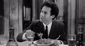 Movie still from “Seduced and Abandoned” (1964), directed by Pietro Germi – A black and white photo of a man eating a plate of pasta; Close Up shot, Low angle