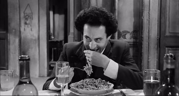 Movie still from “Seduced and Abandoned” (1964), directed by Pietro Germi – A black and white photo of a man eating a plate of pasta; Medium shot, High angle