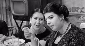 Movie still from “Seduced and Abandoned” (1964), directed by Pietro Germi – A woman and a girl eating food together; Close Up shot, High angle