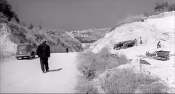 Movie still from “Seduced and Abandoned” (1964), directed by Pietro Germi – A man walking down a snow covered road; Extreme Wide shot, High angle