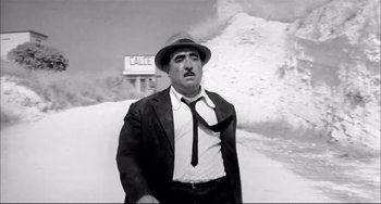 Movie still from “Seduced and Abandoned” (1964), directed by Pietro Germi – A black and white photo of a man wearing a suit and tie; Medium shot, Low angle