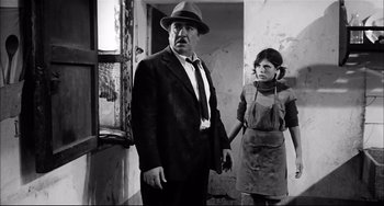 Movie still from “Seduced and Abandoned” (1964), directed by Pietro Germi – A man and a woman standing next to each other in a room; Medium shot, Low angle