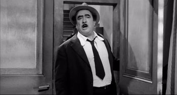 Movie still from “Seduced and Abandoned” (1964), directed by Pietro Germi – A black and white photo of a man in a suit and tie; Medium shot, Low angle