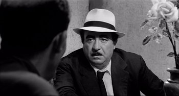 Movie still from “Seduced and Abandoned” (1964), directed by Pietro Germi – A man wearing a white hat talking to another man in a suit; Close Up shot, Over the shoulder angle