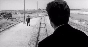 Movie still from “Seduced and Abandoned” (1964), directed by Pietro Germi – A black and white photo of a man standing on a train track; Wide shot, High angle