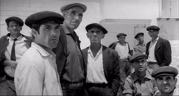 Movie still from “Seduced and Abandoned” (1964), directed by Pietro Germi – Black and white photograph of a group of men in hats; Medium shot, Low angle
